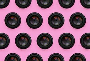 A few camera lenses with a closed aperture lie on texture background of fashion pastel pink color paper in minimal concept. Abstract trendy pattern photo