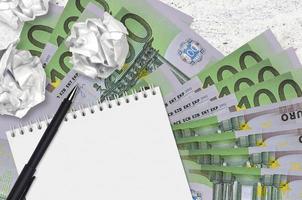 100 Euro bills and balls of crumpled paper with blank notepad. Bad ideas or less of inspiration concept. Searching ideas for investment photo