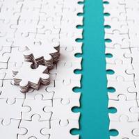 The blue path is laid on the platform of a white folded jigsaw puzzle. The missing elements of the puzzle are stacked nearby. Texture image with space for text photo