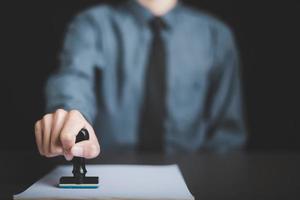 A young executive is stamping on documents for a business contract. Transaction and document management concepts include negotiating corporate entities and filling out legal forms or agreements. photo