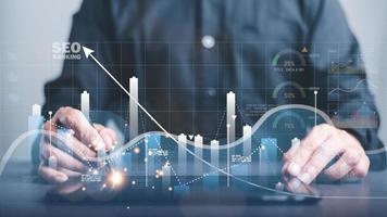 A marketer holds a pen pointing to a graph and shows SEO concepts, optimization analysis tools, search engine rankings, social media sites based on results analysis data. photo