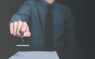 A young executive is stamping on documents for a business contract. Transaction and document management concepts include negotiating corporate entities and filling out legal forms or agreements. photo