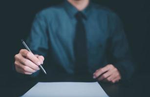 Businessman holding pen at desk, business document management concept and agreement,signing a business contract approval of contract documents confirmation or warranty certificate,employment idea photo