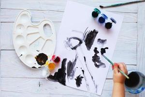 view from above. child draws a brush and paints top view. Flat lay art tools for painting.Artwork workplace photo