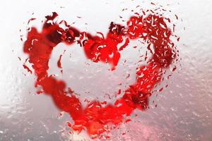 Red heart under glass surface with water drops close. Valentines background, love, date concept photo