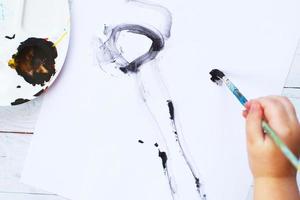 view from above. child draws a brush and paints top view. Flat lay art tools for painting.Artwork workplace photo