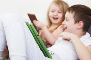 kids with tablet and smartphones in bed at home. Distance learning online education. children playing with gadgets. photo