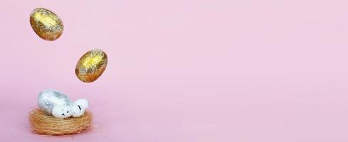 Gold and silver Easter eggs levitation to the nest on a pink background. Easter concept. Copy space photo
