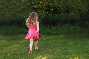 bebé feliz sonriendo. niña corriendo en una puesta de sol al aire libre foto