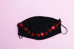 surgical Medical face mask and red heart on pink background. Healthcare and valentines day concept. photo