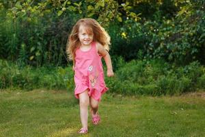 bebé feliz sonriendo. niña corriendo en una puesta de sol al aire libre foto