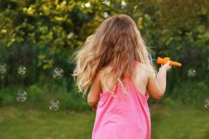 Cute little girl is blowing soap bubbles photo