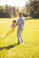 Padre con hija divirtiéndose en el césped del parque foto