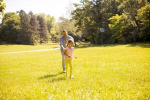 Father chasing his little daughter while playing in the park photo