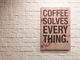 Inspirational motivating quote about coffee on canvas frame hanging on brick wall in the cafe photo