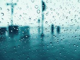 Drops of rain on glass window with blue toned color photo