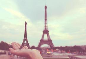 Hand holding eiffel tower model in paris, retro filter effect photo