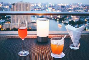 copas de cóctel con luz de velas en el bar de la azotea con vistas a la ciudad foto