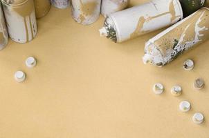 Some used orange aerosol spray cans and nozzles with paint drips lies on a blanket of soft and furry light orange fleece fabric. Classic fashion design color. Graffiti hooliganism concept photo