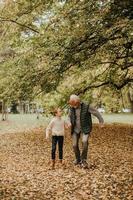 Grandfather spending time with his granddaughter in park on autumn day photo