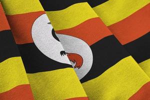 Uganda flag with big folds waving close up under the studio light indoors. The official symbols and colors in banner photo