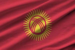 Kyrgyzstan flag with big folds waving close up under the studio light indoors. The official symbols and colors in banner photo