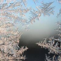 Snowflakes frost rime macro on window glass pane photo