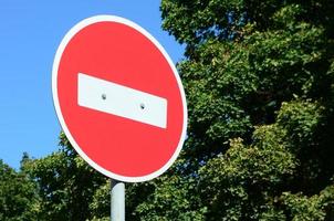 A circular red sign with a white bar indicating NO ENTRY on a grey metal post photo