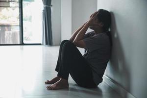 Schizophrenia with lonely and sad in mental health depression concept. Depressed woman sitting against wall at home with a shadow on wall feeling miserable. Women are depressed, fearful and unhappy. photo