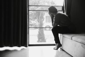 esquizofrenia con soledad y tristeza en el concepto de depresión de salud mental. mujer deprimida sentada en el sofá de casa con una habitación oscura sintiéndose miserable. las mujeres están deprimidas, temerosas e infelices. foto