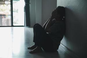 Schizophrenia with lonely and sad in mental health depression concept. Depressed woman sitting against wall at home with a shadow on wall feeling miserable. Women are depressed, fearful and unhappy. photo