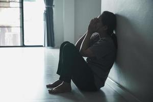 Schizophrenia with lonely and sad in mental health depression concept. Depressed woman sitting against wall at home with a shadow on wall feeling miserable. Women are depressed, fearful and unhappy. photo