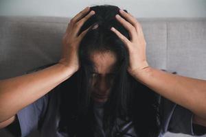 Schizophrenia with lonely and sad in mental health depression concept. Depressed woman sitting against on the sofa at home with dark room feeling miserable. Women are depressed, fearful and unhappy. photo