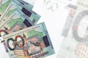 100 Belorussian rubles bills lies in stack on background of big semi-transparent banknote. Abstract business background photo