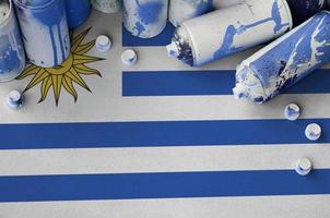 bandera de uruguay y pocas latas de aerosol usadas para pintar graffiti. concepto de cultura de arte callejero foto