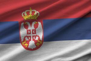 Serbia flag with big folds waving close up under the studio light indoors. The official symbols and colors in banner photo