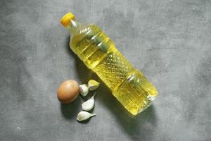 bottled cooking oil and herbs on concrete background photo