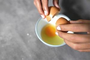 someone is breaking eggs to make omlette on a concrete background photo