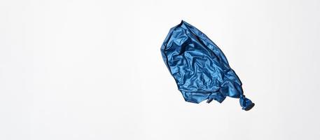 Bursting blue balloon on a white background, top view. Banner, copy space. End of holiday concept, unsuccessful party photo