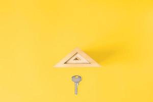 Flat lay metal key and toy roof, copy space. Creative concept of buying  a house, renting real estate photo