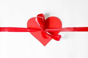 Red ribbon with a bow tied at the heart, flat lay. Concept heart as a gift. photo