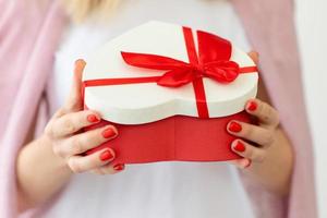 Valentine's day, holiday and gift concept. Close up hands of woman hold and open gift box red heart for Valentines Day.Delivery present. Surprise photo