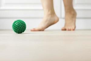 mujer haciendo ejercicio gimnástico de corrección de pie plano usando pelota de masaje en casa tema de relajación miofascial de prevenir la fatiga del pie después de usar zapatos de tacón alto pelota antiestrés foto