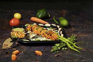 Paneer tikka is an Indian dish made from chunks of paneer with sauce and  vegetables on the table photo