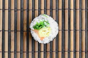 Sushi roll lie on a bamboo straw serwing mat. Traditional Asian food. Top view. Flat lay minimalism shot with copy space photo