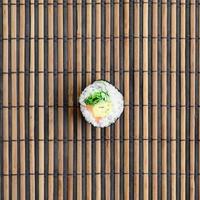 Sushi roll lie on a bamboo straw serwing mat. Traditional Asian food. Top view. Flat lay minimalism shot with copy space photo