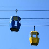 Blue and yellow passenger cable way cabins in the clear sky photo