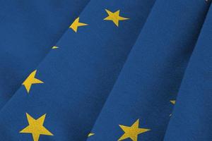 bandera de la unión europea con grandes pliegues ondeando de cerca bajo la luz del estudio en el interior. los símbolos y colores oficiales en banner foto