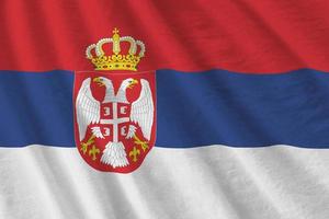 Serbia flag with big folds waving close up under the studio light indoors. The official symbols and colors in banner photo