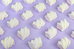 Colorful marshmallow laid out on violet paper background. pastel creative textured pattern. Perspective macro shot photo